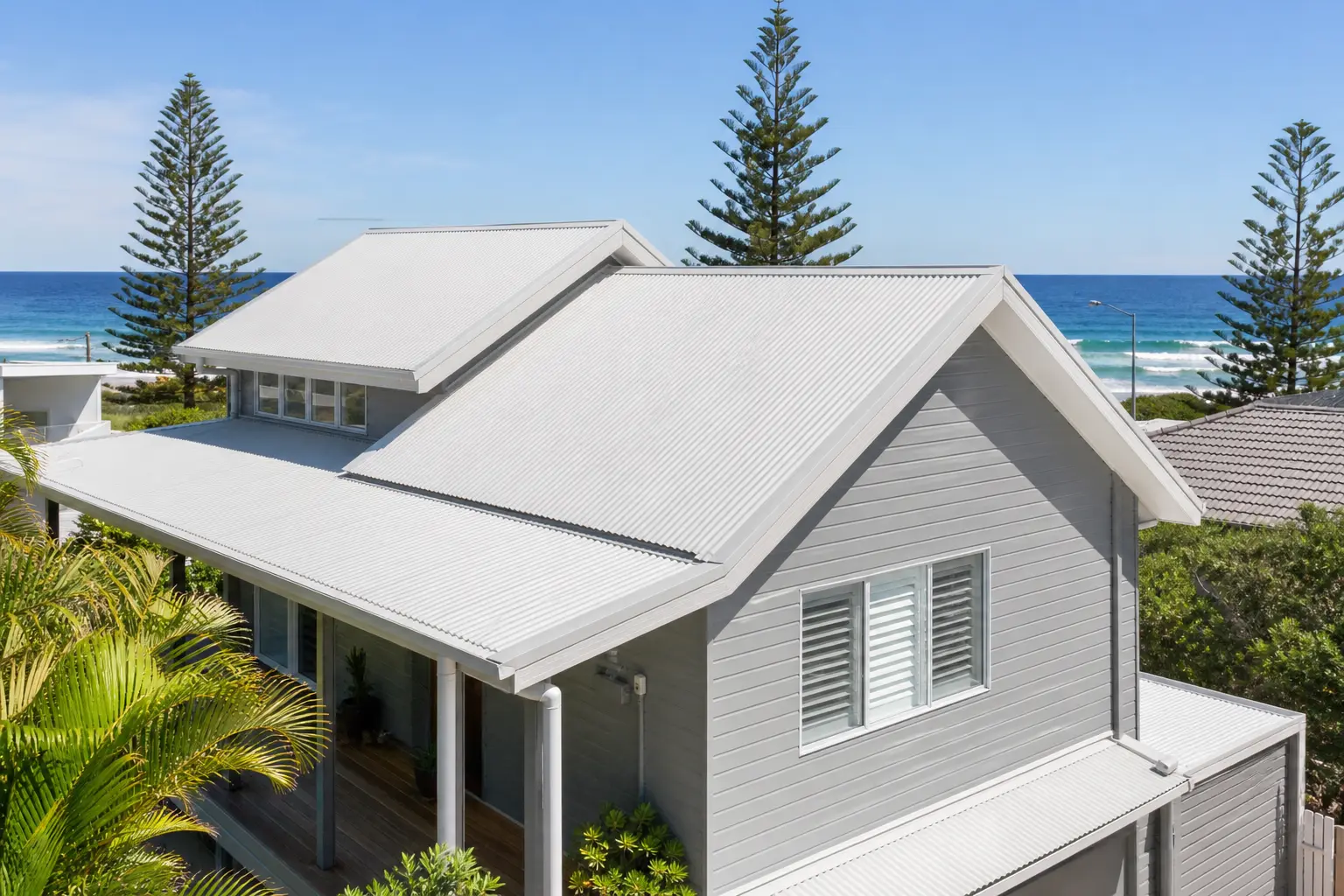 Illustration: coastal home with a white corrugated metal roof, ocean and Norfolk Island pines behind