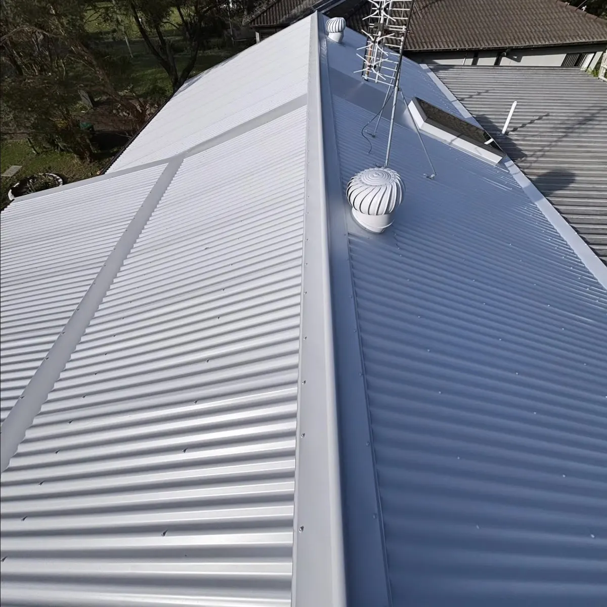 New grey corrugated roof with a whirlybird and skylight