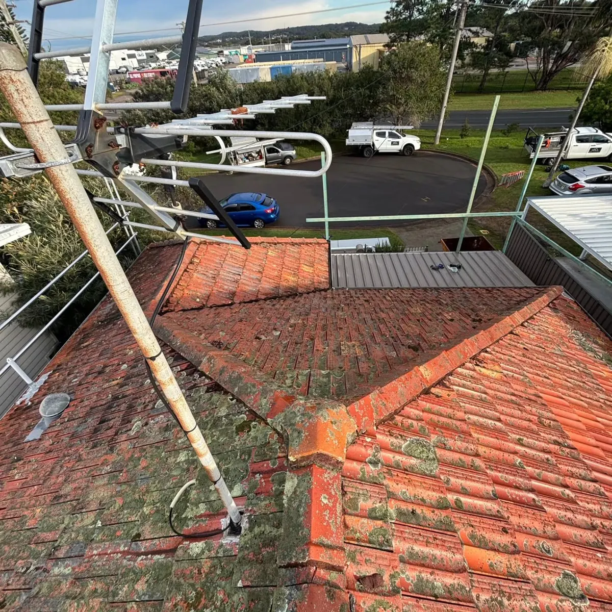 An old terracotta tile roof covered in moss, before a re-roof